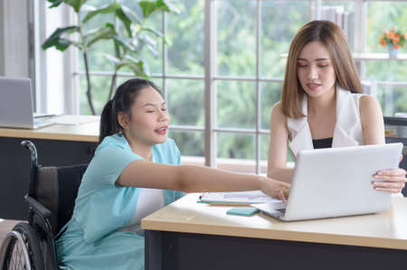Young disabled Asian businesswoman working and meeting together with her colleague in office workplaceの写真素材