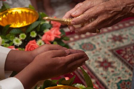 thai wedding ceremony - bridegroom praying for holy waterの写真素材