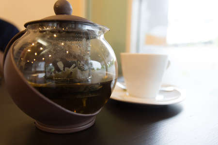 brown hot tea pot on table with white cupの写真素材