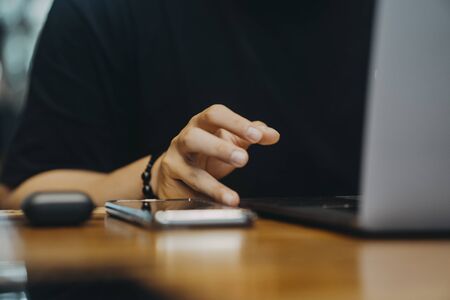 Asian Man wearing medical mask in a coffee using phone and laptop in Ho Chi Minh city, Vietnam