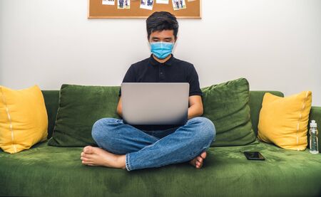 An asian men is working from home during Coronavirus or Covid-19 quarantine, coronavirus covid 19 infected patient in coronavirus covid 19 quarantine room using computerの写真素材