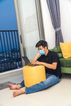 An asian men is working from home during Coronavirus or Covid-19 quarantine, coronavirus covid 19 infected patient in coronavirus covid 19 quarantine room using computerの写真素材