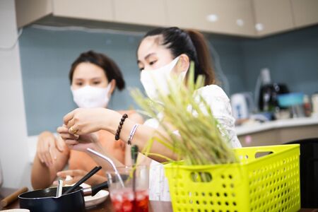 two young women cooking the tapioca dumpling in quarantine for coronavirus wearing protective mask during covid-19 pandemicの写真素材