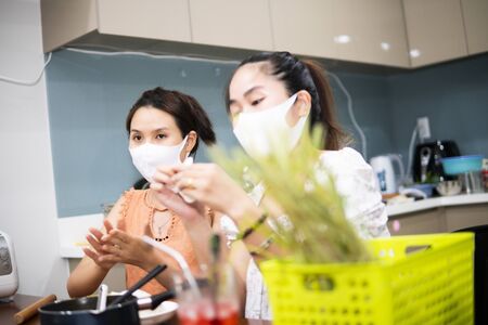 two young women cooking the tapioca dumpling in quarantine for coronavirus wearing protective mask during covid-19 pandemicの写真素材