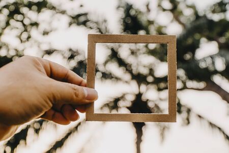 Hand holding blank paper frame with nature bokeh background. Text concept.の写真素材