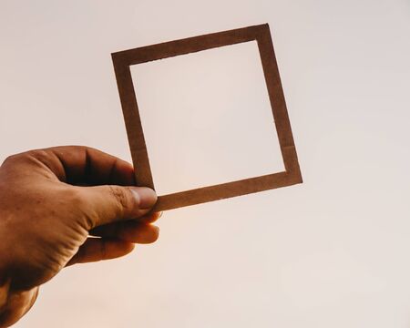 Hand holding blank paper frame with nature bokeh background. Text concept.の写真素材