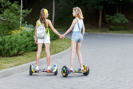 Happy girls riding on hover boards or gyroscooters outdoors at sunset in summer. Active life conceptの写真素材