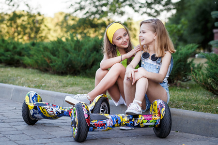 Happy girls riding on hover boards or gyroscooters outdoors at sunset in summer. Active life conceptの写真素材