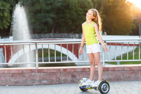Happy girl riding on hover board or gyroscooter outdoors at sunset in summer. Active life conceptの写真素材