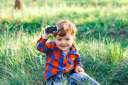 A cute boy having fun outside in the country in summer at the sunset. a boy playing with yellow dandelions in the gardenの写真素材