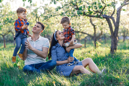 Happy young family spending time together outside in green nature. Parents playing with twins outside.の写真素材