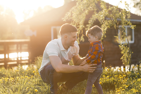 Father and his son having fun outside in summer hugging and laughing. Father taking care of his childの写真素材