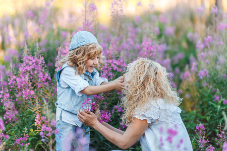 mother and a cute little son hugging and having fun in the fild with flowers in summer. Family and happiness conseptの写真素材