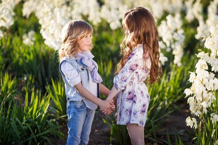 Brother and sister hugging in the field of white Yucca flowers and having fun. Family, friendship, and happiness conceptの写真素材