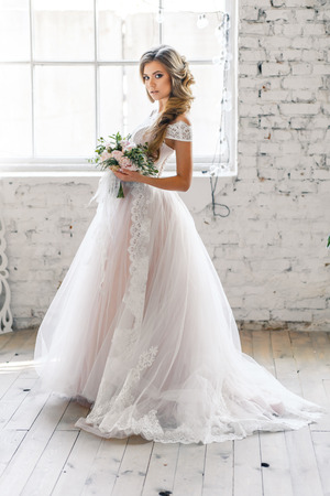 A bride with hairstyle and make up in gorgeous pink wedding dress and a vail with a bouquet of peonies.の写真素材