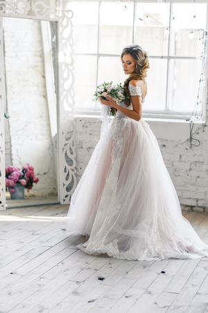 A bride with hairstyle and make up in gorgeous pink wedding dress and a vail with a bouquet of peonies.の写真素材