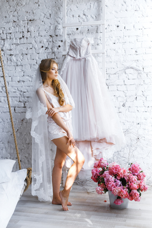 A bride with hairstyle and make up in gorgeous pink wedding dress and a vail with a bouquet of peonies.の写真素材