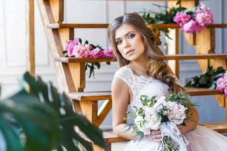 A bride with hairstyle and make up in gorgeous pink wedding dress and a vail with a bouquet of peonies.の写真素材