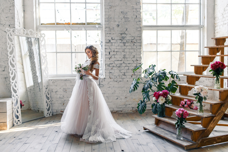 A bride with hairstyle and make up in gorgeous pink wedding dress and a vail with a bouquet of peonies.の写真素材