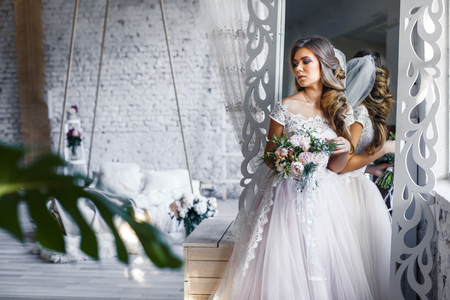 A bride with hairstyle and make up in gorgeous pink wedding dress and a vail with a bouquet of peonies.の写真素材