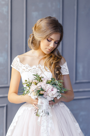 A bride with hairstyle and make up in gorgeous pink wedding dress and a vail with a bouquet of peonies.の写真素材