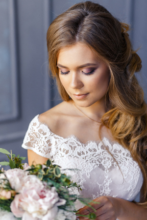 A bride with hairstyle and make up in gorgeous pink wedding dress and a vail with a bouquet of peonies.の写真素材