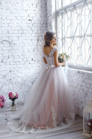 A bride with hairstyle and make up in gorgeous pink wedding dress and a vail with a bouquet of peonies.の写真素材