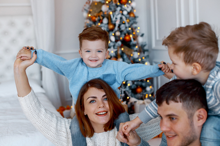 A family of four hugging in front of the christmas tree. love, happiness and big family conceptの写真素材