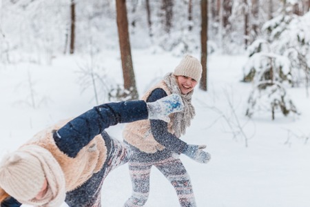 Beautiful teenage girls twins sisters having fun outside in a wood with snow in winter. Friendship,...