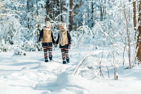 Beautiful teenage girls twins sisters having fun outside in a wood with snow in winter. Friendship,...