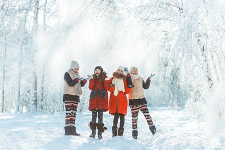 Beautiful teenage girls having fun outside in a wood with snow in winter. Friendship and active life conseptの写真素材