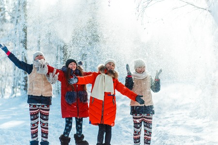 Beautiful teenage girls having fun outside in a wood with snow in winter. Friendship and active life conseptの写真素材