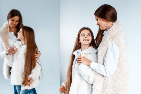 Stylish beautiful mother and a cute daughter with blue eyes in studio hugging and having fun. love and family conceptの写真素材