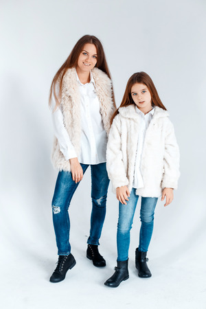 Stylish beautiful mother and a cute daughter with blue eyes in studio hugging and having fun. love and family conceptの写真素材