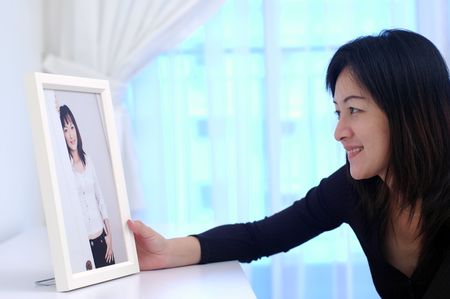 An asian chinese lady admiring her photo at home