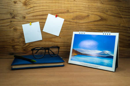 blank paper note on wood background with diary book pen and glassesの写真素材