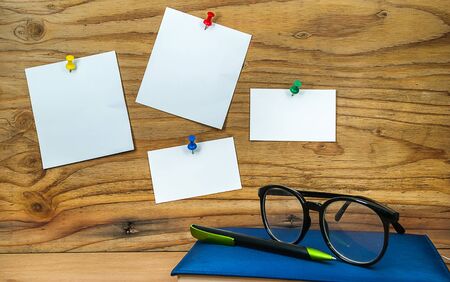 blank paper note on wood background with diary book pen and glasses