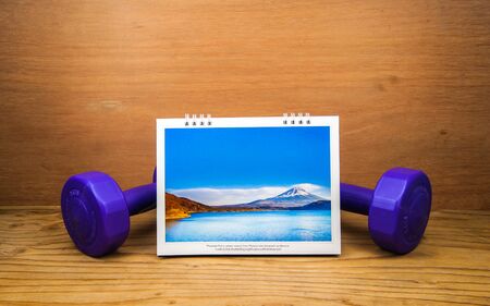 blank table Calendar page with cameasuring tape fitness dumbbell on wood backgroundの写真素材