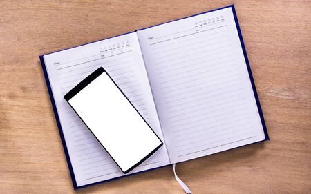 top view of open book with smart phone and  stationery on wood office desk