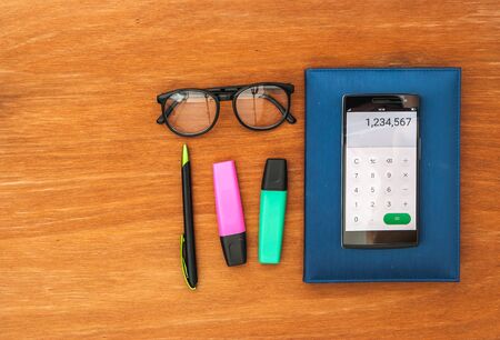 top view of office desk with smart phone open calculator appの写真素材
