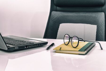 office desk with stationery notebook,on white table and black chairの写真素材