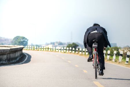 Asian businessman riding bicycle on the road