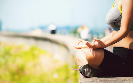 Portrait of a beautiful young asian woman sitting in yoga pose at the parkの写真素材