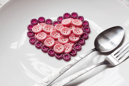 A dish of buttons which is in shape of heart with spoon and forkの写真素材