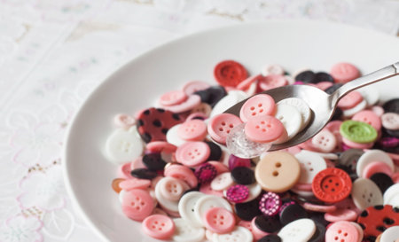 A white dish of buttons with many kinds and colors of buttonsの写真素材