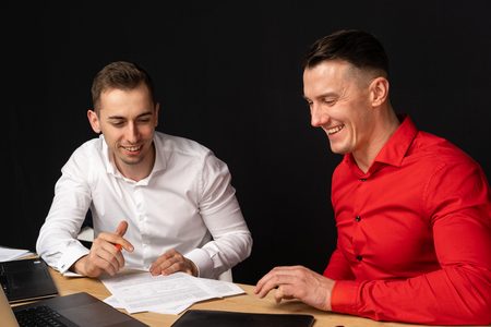 Image of two young businessmen using laptop at meetingの写真素材