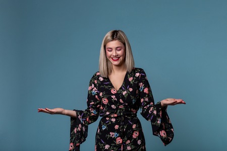 Blonde young woman in spring dress showing open palm with copy space for prodact