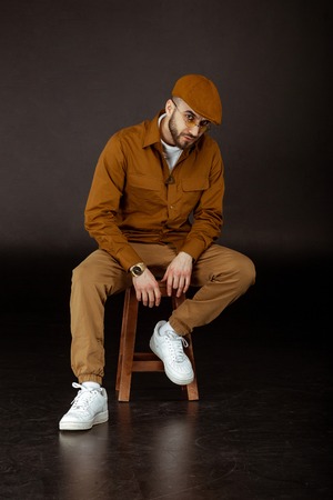 Young pencive man in beige hat and shirt, yellowe sunglasses