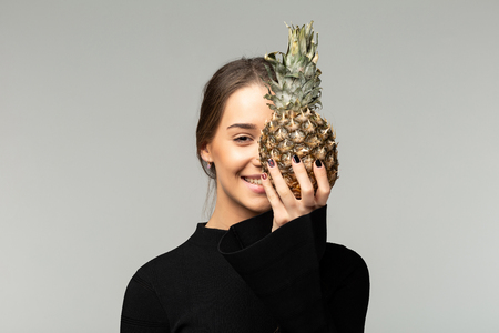 Funny young beautiful smiling girl with a pineappleの写真素材