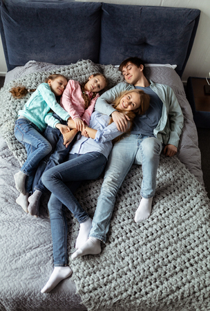 Photo of loving young family of four lying on bedの写真素材